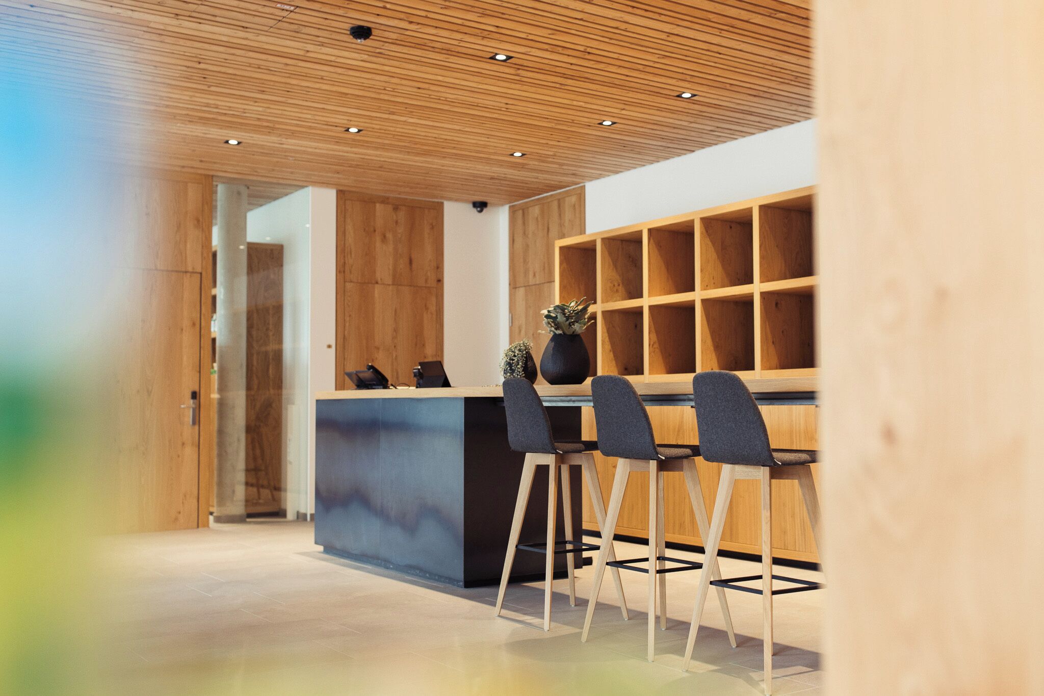 Un interior moderno con techo de madera, una recepción y un área de estar con sillas.