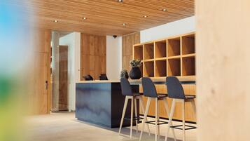Un interior moderno con techo de madera, una recepción y un área de estar con sillas.
