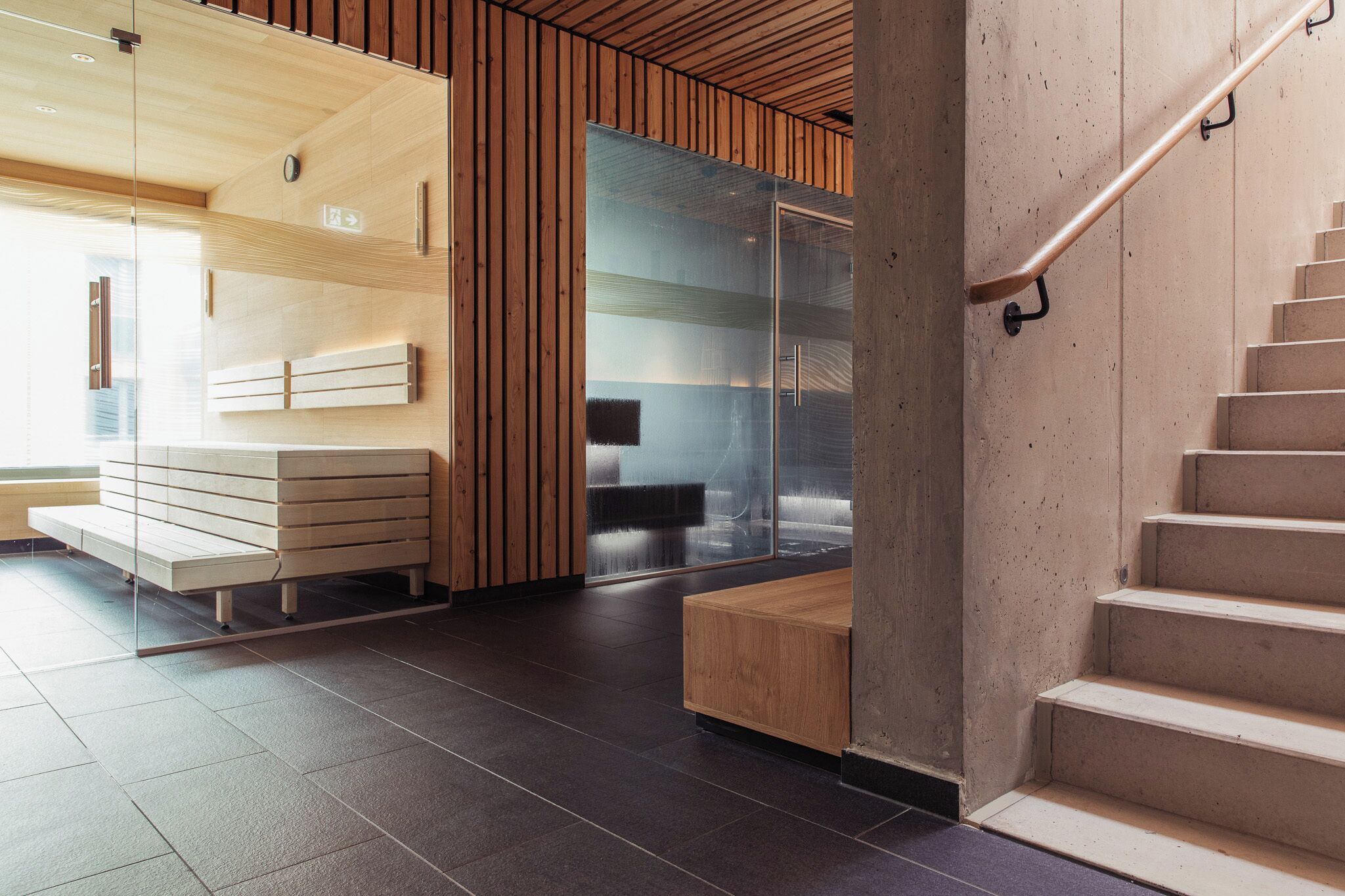 A modern interior with a wooden bench, a glass partition, and a staircase.