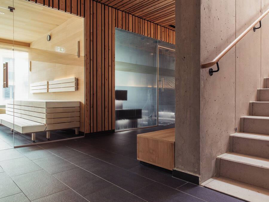 A modern interior with a wooden bench, a glass partition, and a staircase.