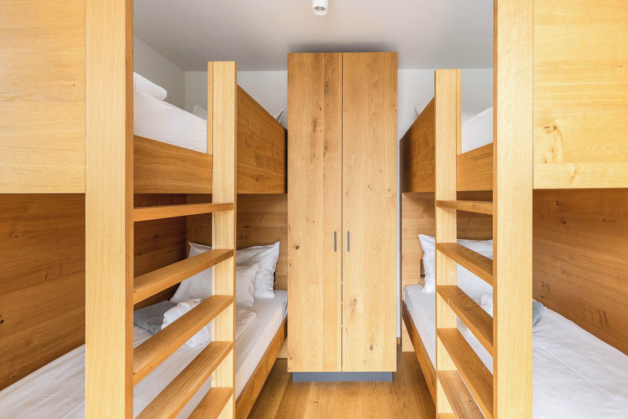 Een slaapkamer met stapelbed, een centrale garderobe en een plafondlamp.