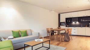 Un salon moderne comprenant un canapé, une table basse et un coin repas avec des chaises.