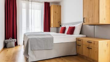Un dormitorio con una cama, armarios de madera, una manta gris y un bolso de mano gris.