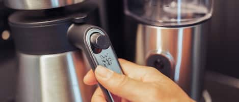 Une main actionne une machine à café dotée d’un panneau de commande.