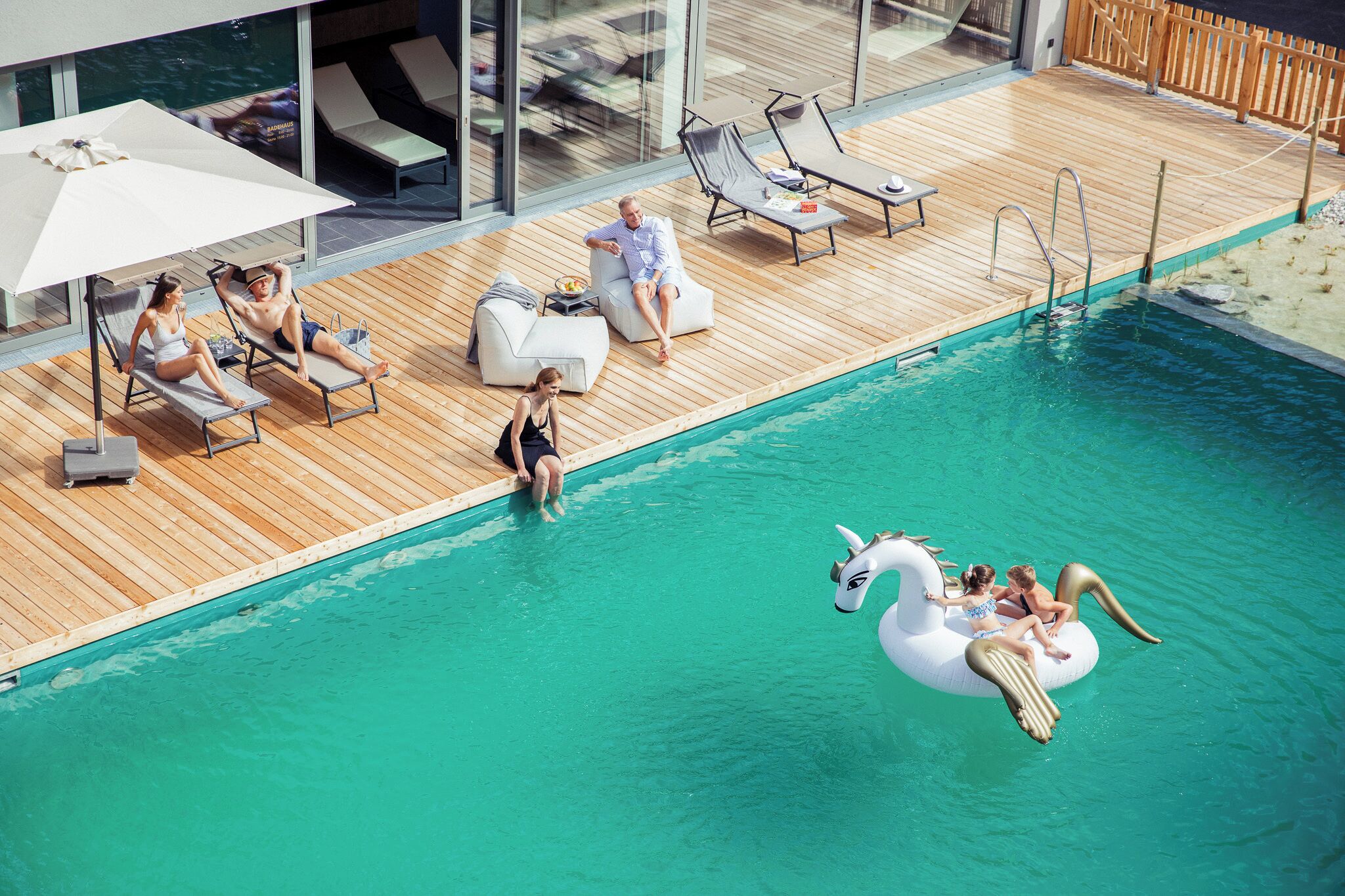 Un área junto a la piscina con sillones de descanso y una decoración de cisne flotante.