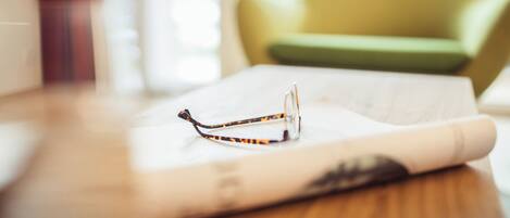 Un par de gafas sobre una superficie blanca, con un fondo desenfocado de una habitación.