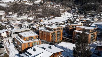 Una zona residencial nevada con edificios modernos, incluyendo una estructura de madera destacada con balcones.