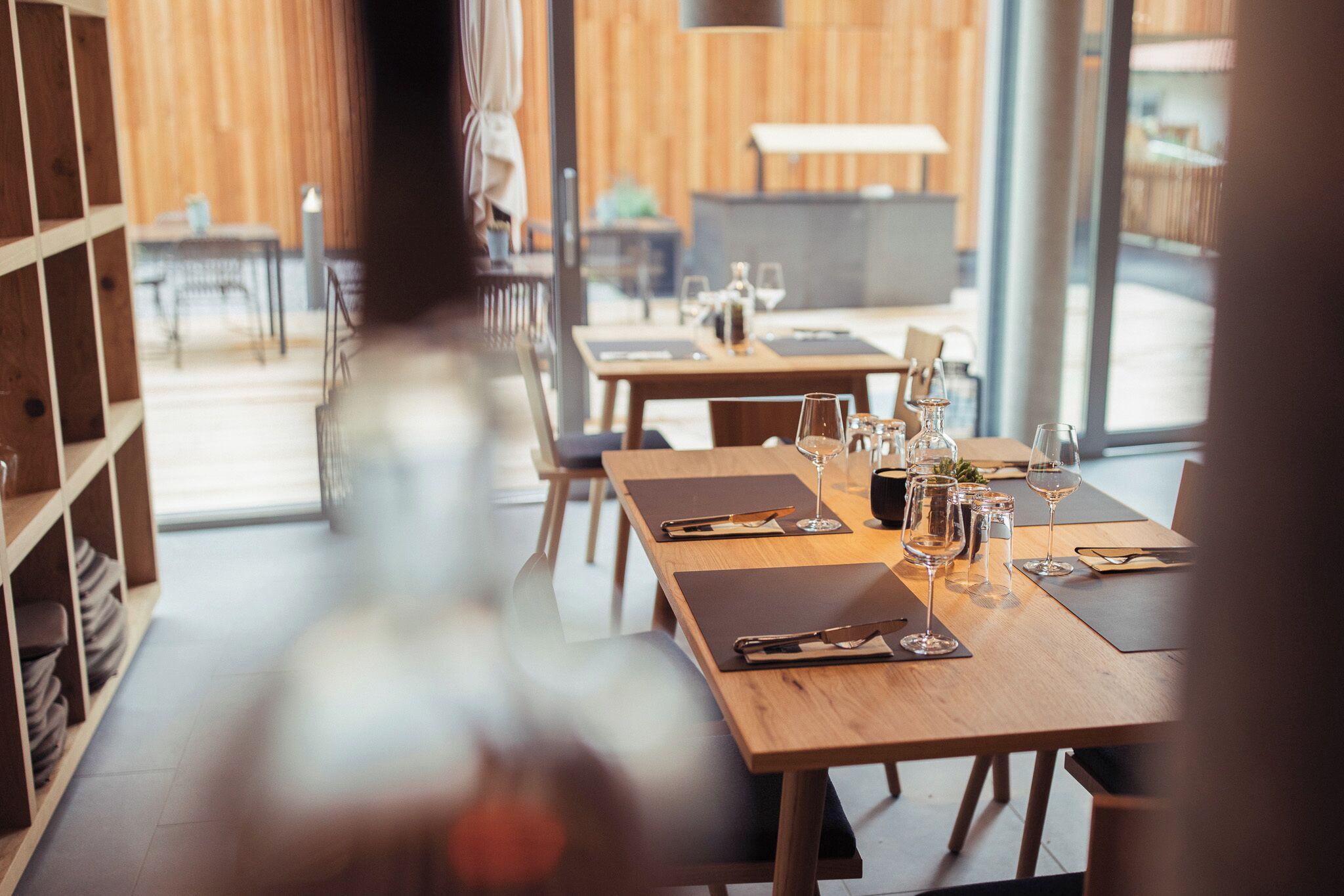 L’intérieur d’un restaurant avec des tables et des chaises en bois, et une vue sur l’extérieur.