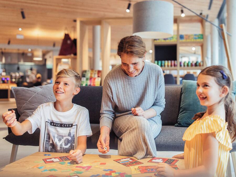 A family seated at a table with educational materials, in a modern indoor setting with a visible store in the background.