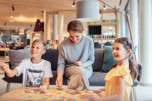 A family seated at a table with educational materials, in a modern indoor setting with a visible store in the background. - All Suite Resort Ötztal (Oetz)
