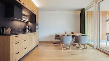 Eine moderne Küche mit Holzschränken, einem eingebauten Ofen und einem Essbereich mit Tisch und Stühlen.
