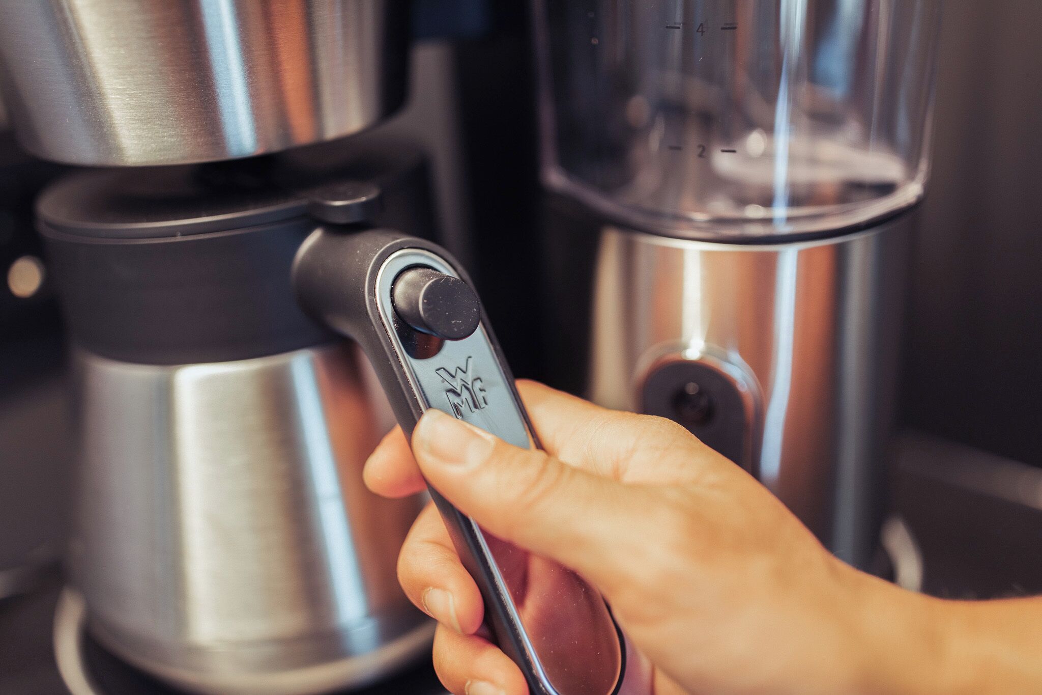Een hand bedient een koffieapparaat met een digitaal scherm.