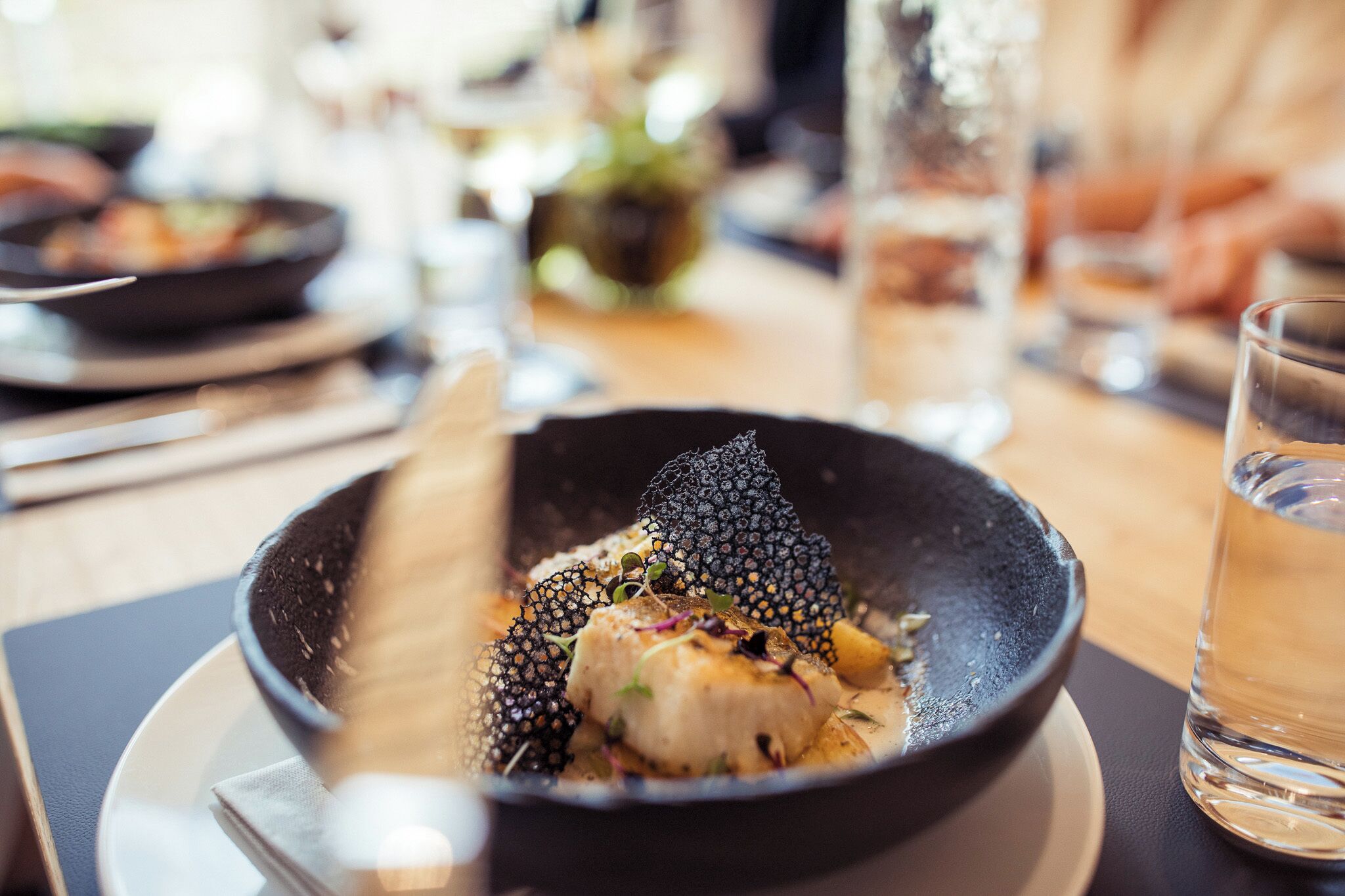A dining table with a bowl of food, a glass of water, and a napkin.