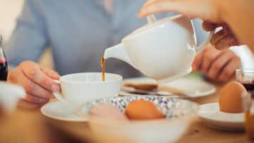 A person pouring a liquid from a teapot into a cup.