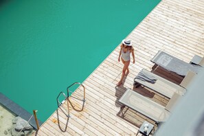 A wooden deck with a pool, lounge chairs, and a diving board. - All Suite Resort Ötztal (Oetz)