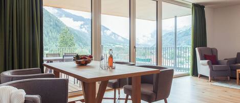 Un comedor con una mesa y sillas de madera, un bol de fruta y una botella.