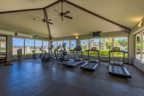 A gym with treadmills, elliptical machines, and a ceiling fan.