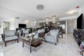 Un salon moderne avec un sol en marbre, des canapés à rayures, une table basse en verre et un lustre.