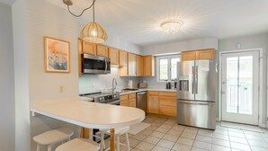 Een moderne keuken met houten kastjes, roestvrijstalen apparatuur en een centraal eiland met krukken.