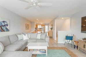 A modern living room with a grey sectional sofa, a white coffee table, and a ceiling fan.