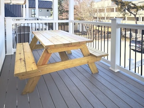 A wooden picnic table on a wooden deck with white railings. - Ocean Block Rehoboth Beach Townhouse Porch Parking (Rehoboth Beach)
