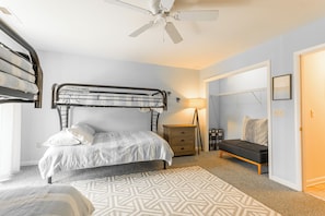 A bedroom with a bunk bed, a bedside table, a lamp, a sofa, and a patterned rug. - Ocean Block Rehoboth Beach Townhouse Porch Parking (Rehoboth Beach)
