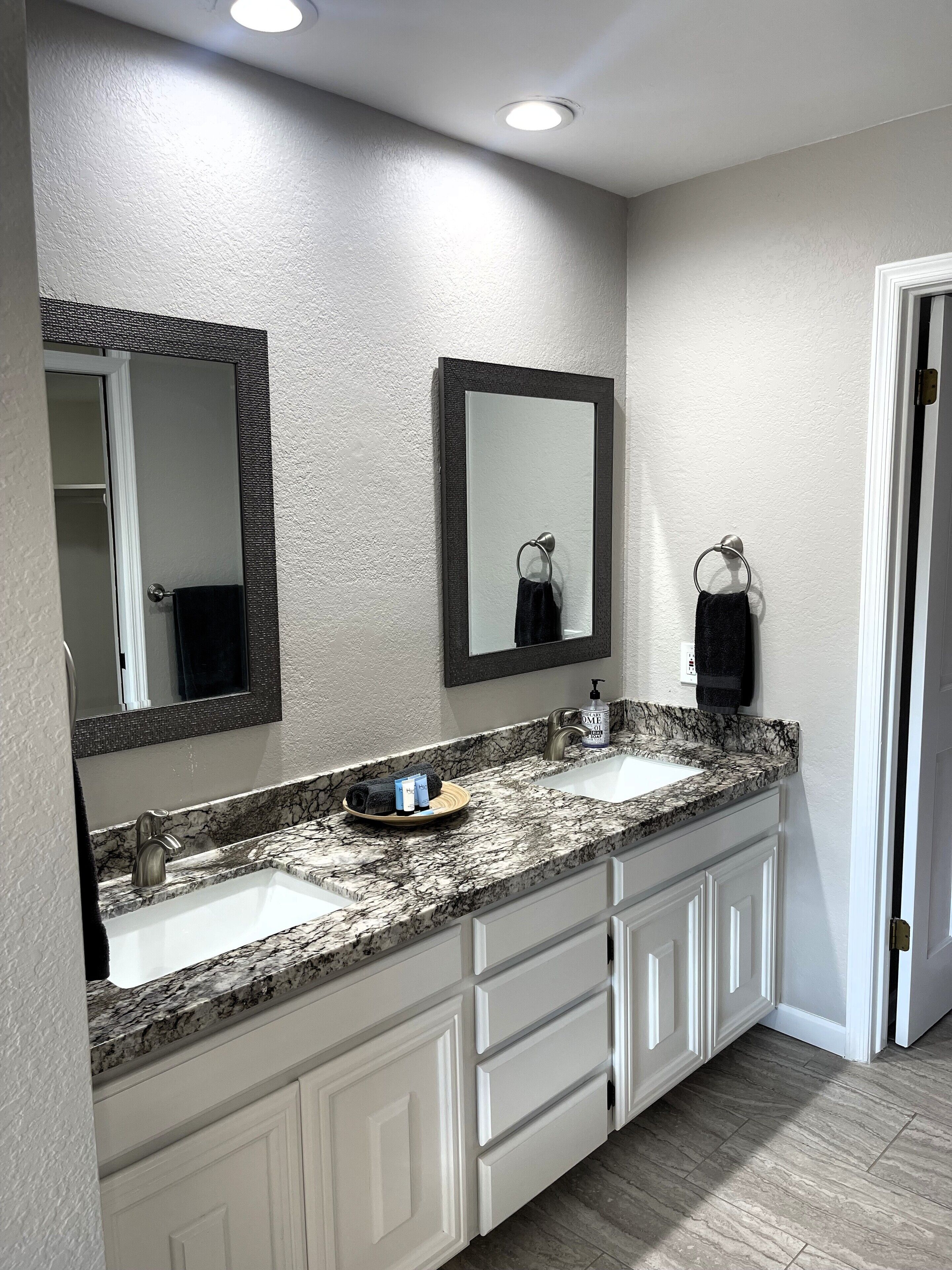 A bathroom with two sinks, a mirror, and a towel rack.