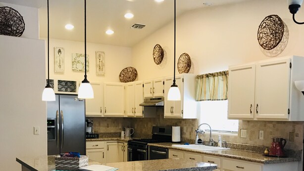 A modern kitchen with a central island, white cabinetry, and pendant lighting. - Enjoy a Relaxing Getaway at our Cottage in Prescott Valley (Prescott Valley)