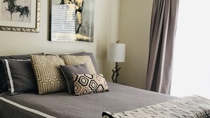 A neatly made bed with patterned pillows, a bedside lamp, and artwork on the wall. - Enjoy a Relaxing Getaway at our Cottage in Prescott Valley (Prescott Valley)