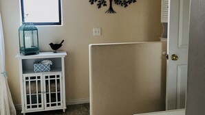 A room with a window, a wall-mounted tree decoration, a white cabinet with glass doors, and a door with a brass handle. - Enjoy a Relaxing Getaway at our Cottage in Prescott Valley (Prescott Valley)