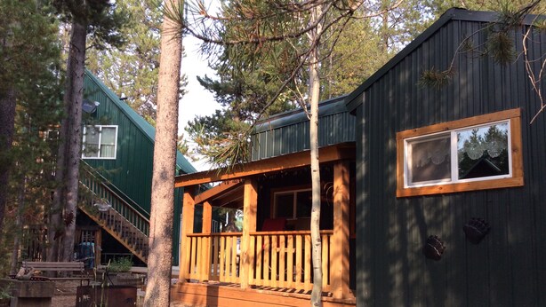 A cabin with a wooden deck, a staircase, and a window.