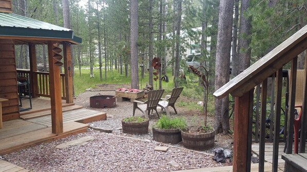 Una terraza de madera con un espacio de estar techado, rodeada de bosque.