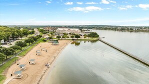 Un hôtel situé au bord d’un lac, doté d’une plage de sable, de tables de pique-nique et d’un sentier pédestre longeant le rivage.