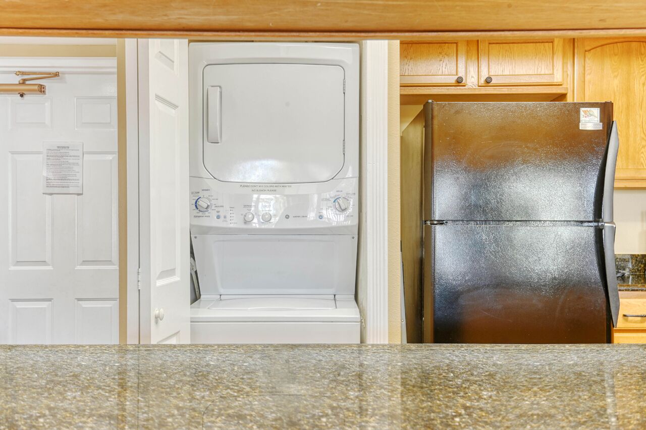 Una cocina con lavavajillas blanco, refrigerador negro y armarios de madera.