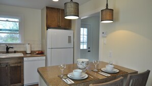 Una cocina con comedor, armarios de madera, un refrigerador blanco y una ventana.