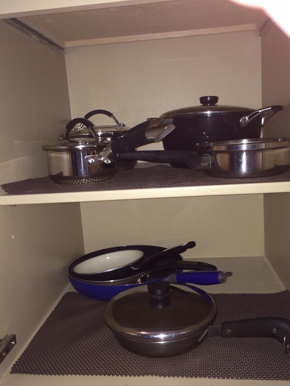 Una cocina con dos estantes, cada uno con diferentes ollas y sartenes.