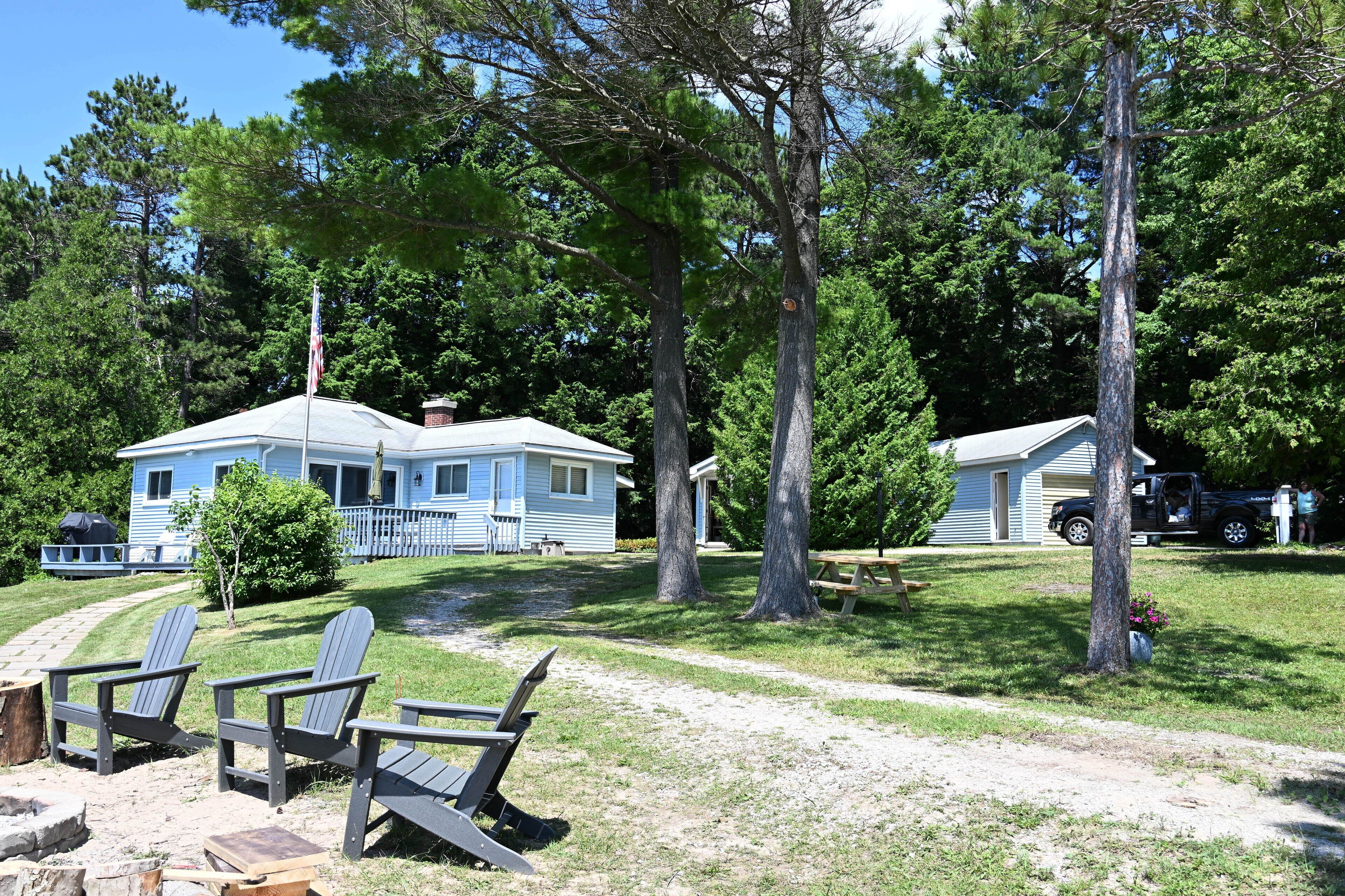 A cabin with a porch, a small deck, and a picnic table.