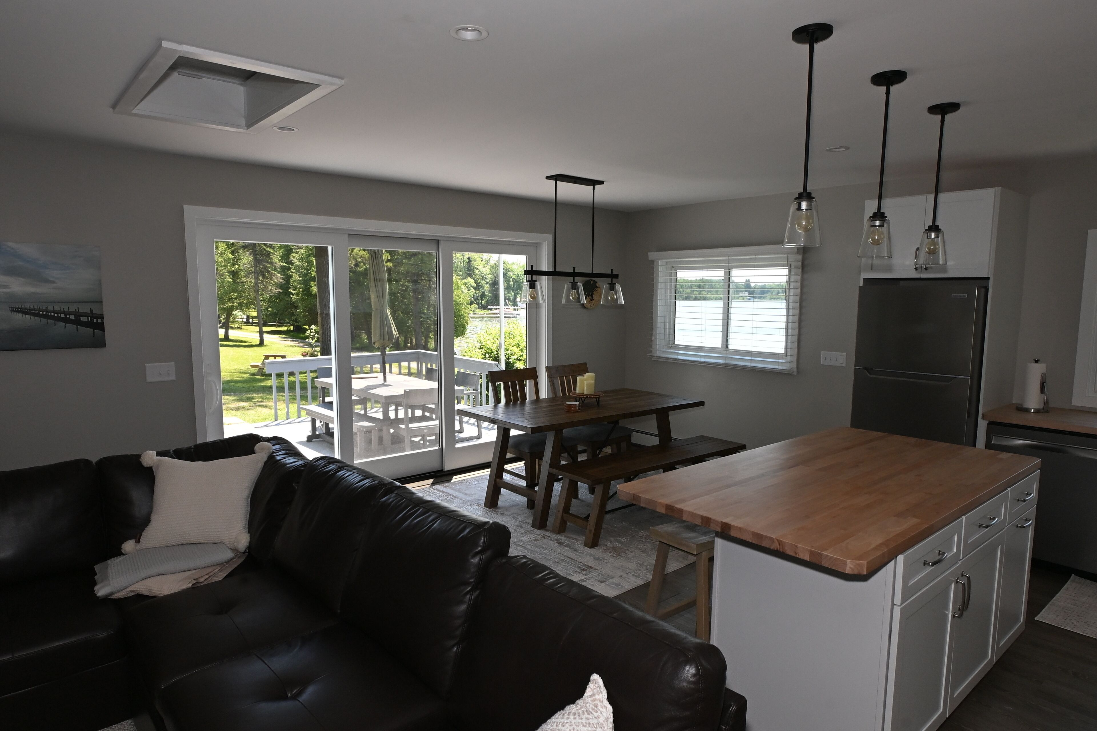 A modern kitchen with a wooden island, stainless steel refrigerator, and pendant lighting.
