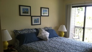 Une chambre à coucher avec une couvre-lit à motifs, deux lampes de chevet et trois tableaux encadrés accrochés au mur.