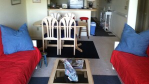 Un espace de vie compact comprenant un coin repas, une kitchenette et une petite table avec un magazine.