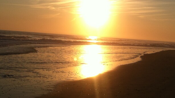 Une scène de plage au coucher du soleil sur l’océan.