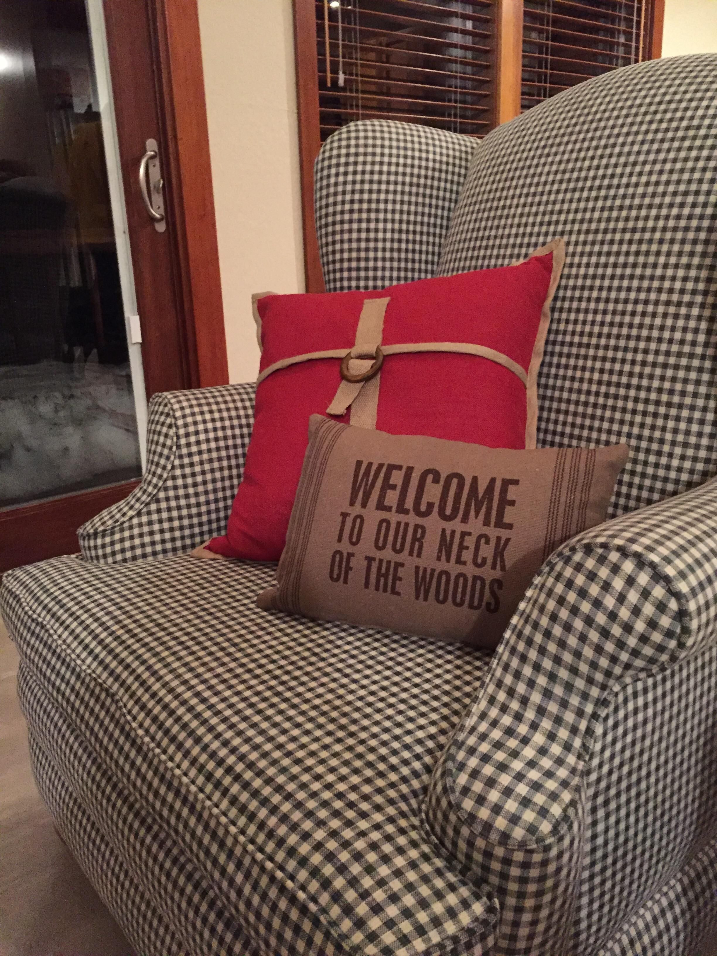 Een geruite fauteuil met een kussen waarop staat: 'WELKOM IN ONZE HOEVE'.