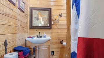 A wooden cabin bathroom with a sink, mirror, and towel rack.