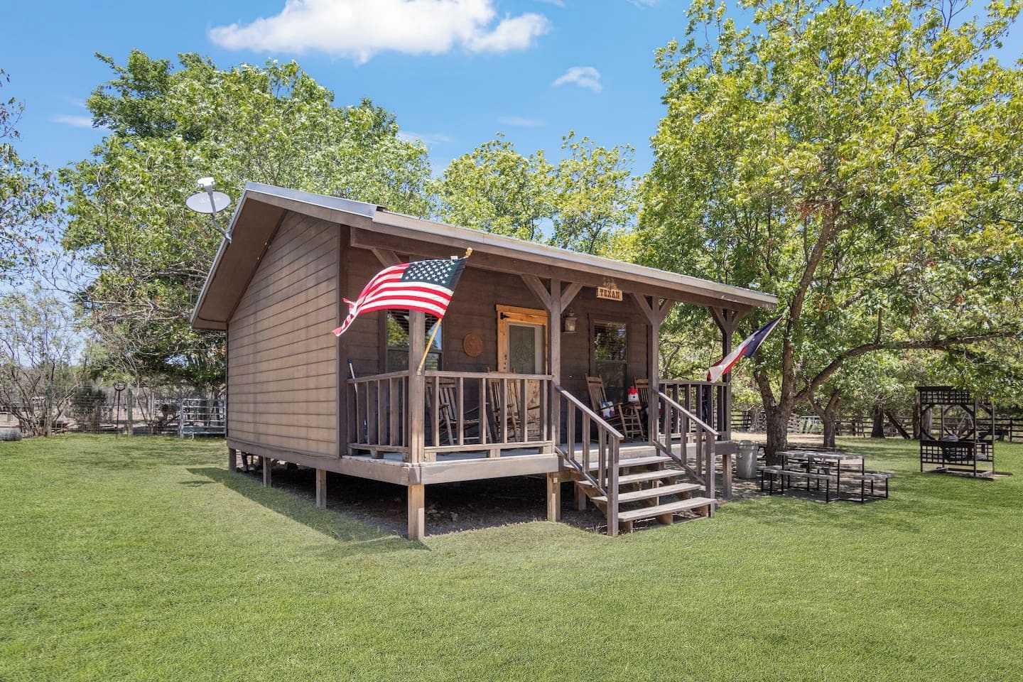 A small wooden cabin with a porch and an American flag.