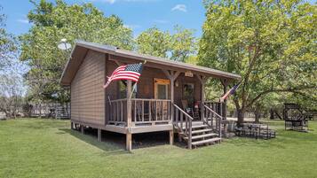 A small wooden cabin with a porch and an American flag.