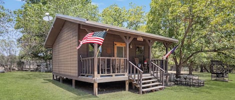 A small wooden cabin with a porch and an American flag.
