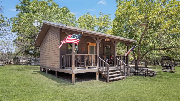 Eine kleine Holzhütte mit Veranda und einer amerikanischen Flagge.