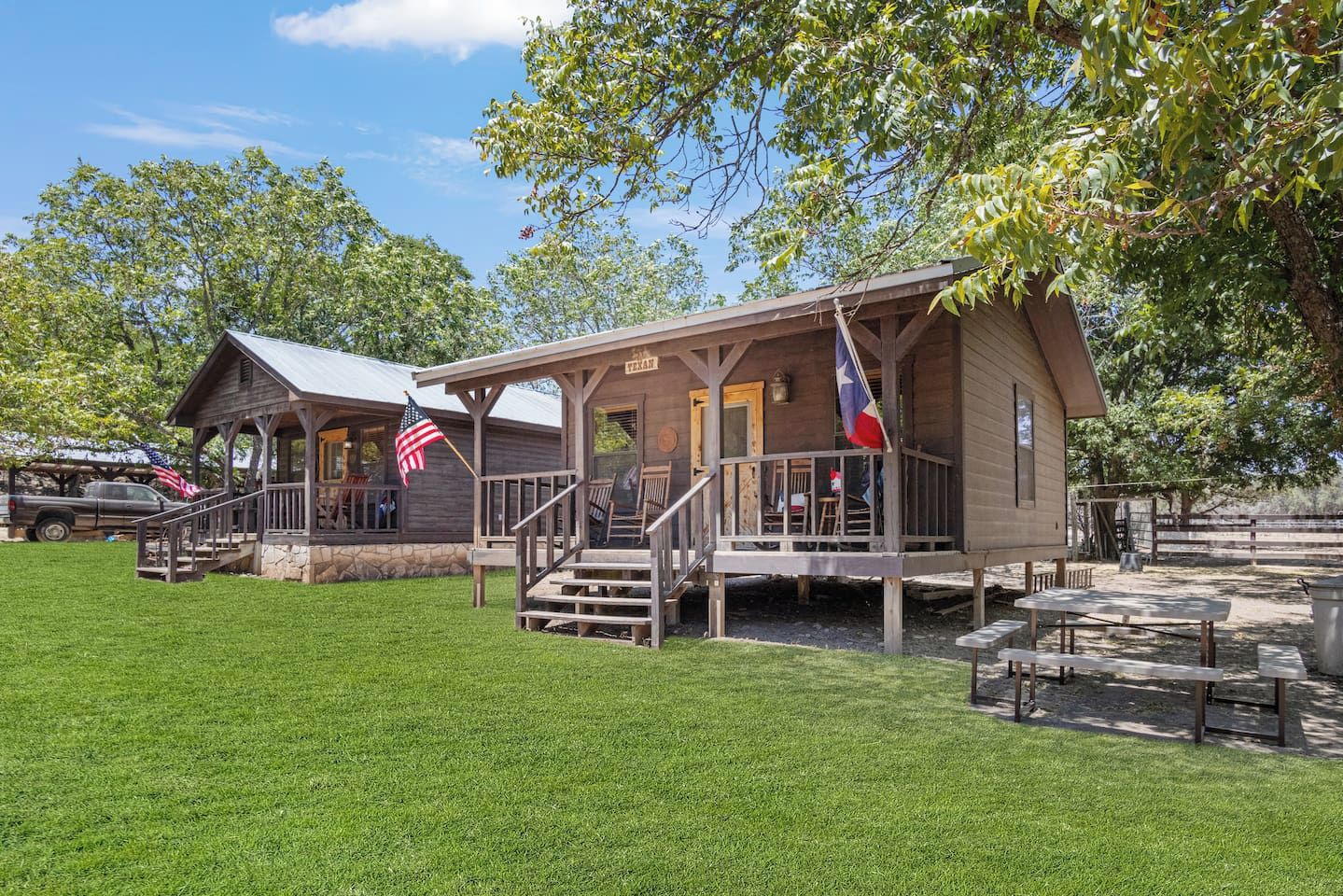 A rustic wooden building with a porch, steps, and a flag.