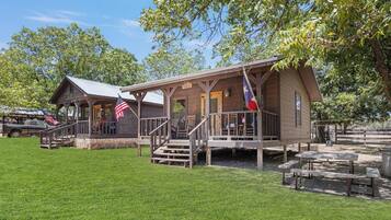 A rustic wooden building with a porch, steps, and a flag.