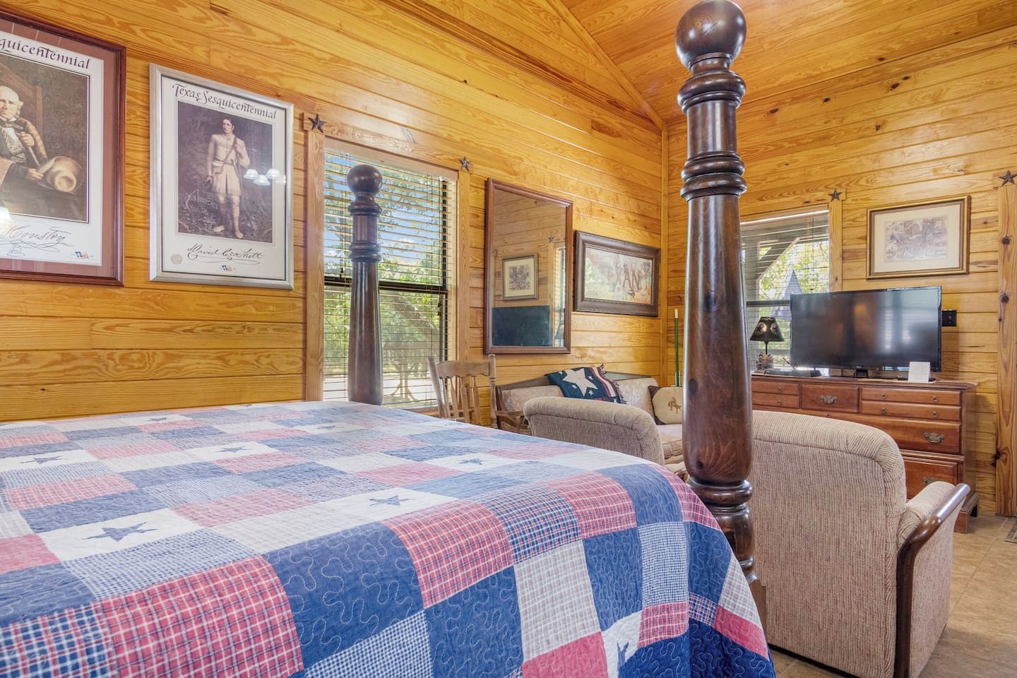 A room with a large bed, a wooden ceiling, a television, and framed pictures on the walls.